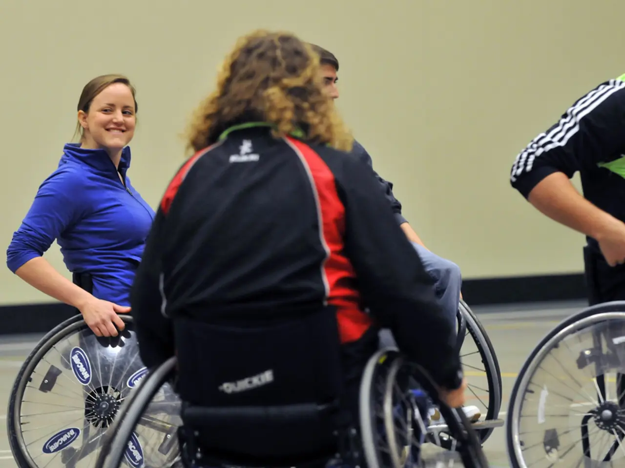 In this image we can see group of people sitting on wheelchairs placed on the ground. One woman...