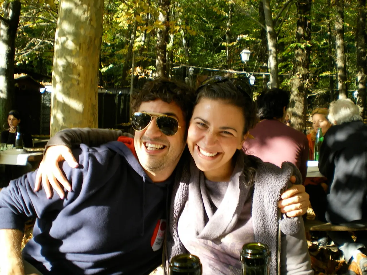 In the foreground of this image, there is a couple sitting and hugging each other and they are...