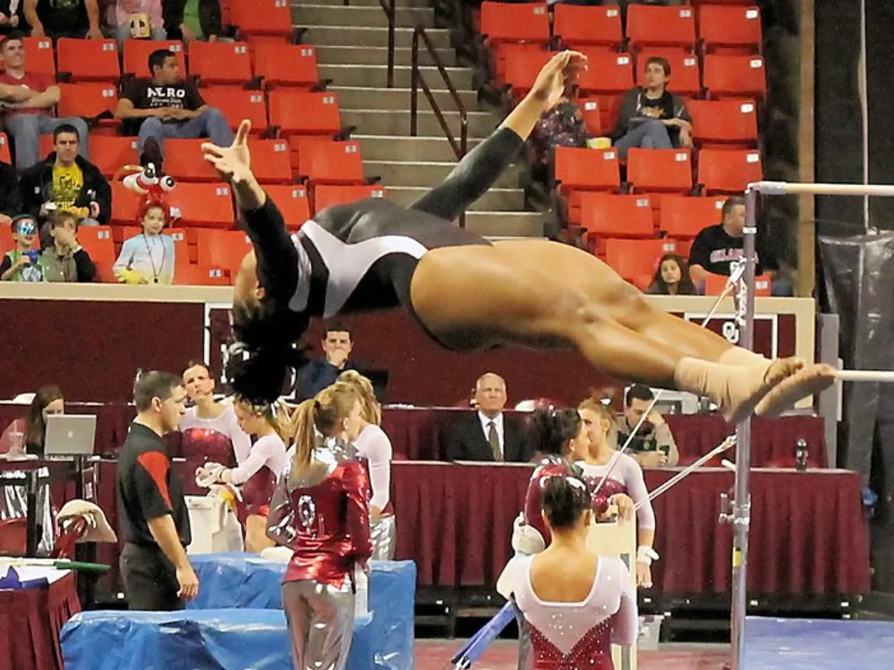 In this image, we can see persons wearing clothes. There are some persons sitting on seats. There...