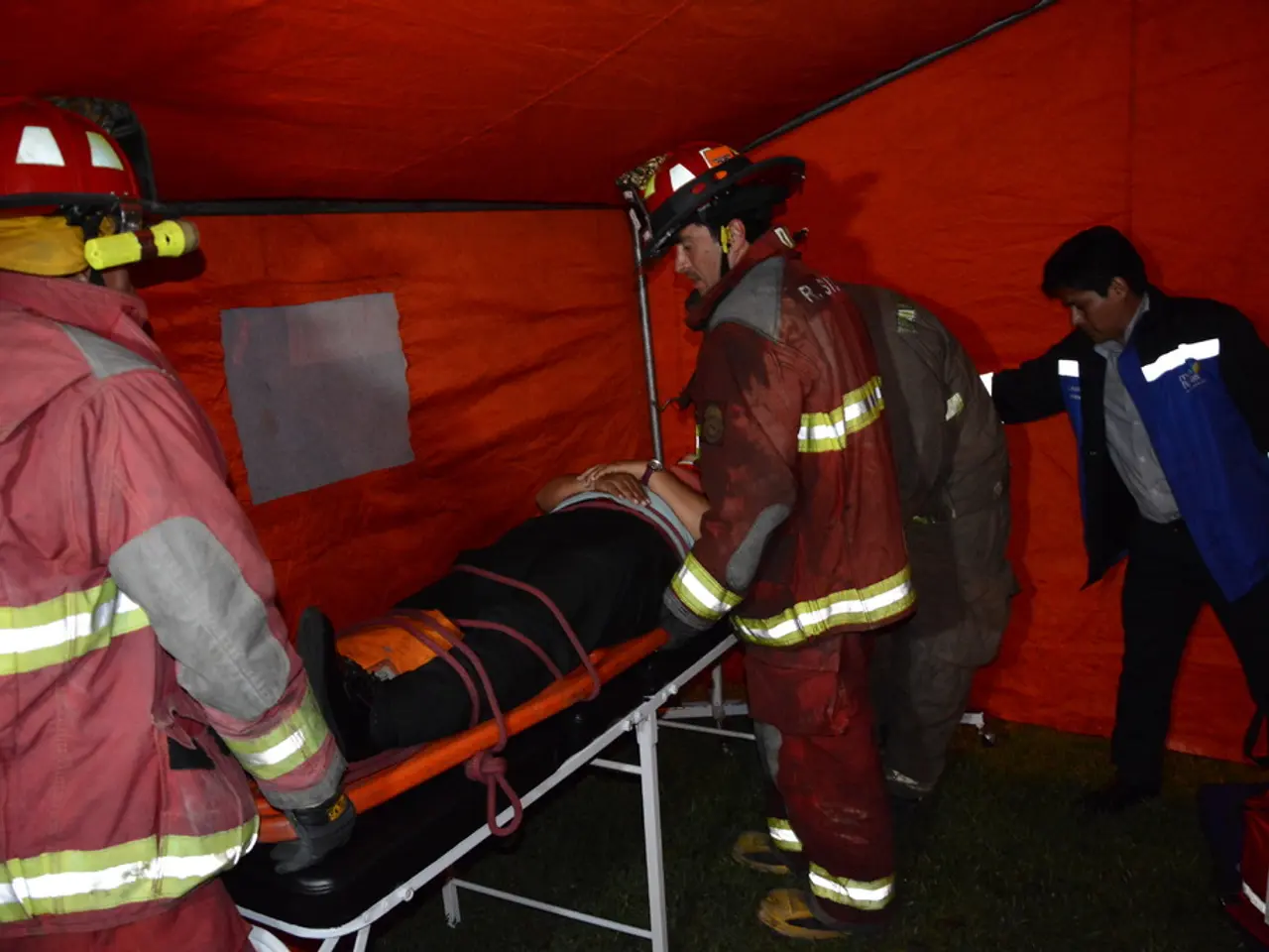In the foreground of this image, there is a tent. Under it, there is a man on the stretcher and...