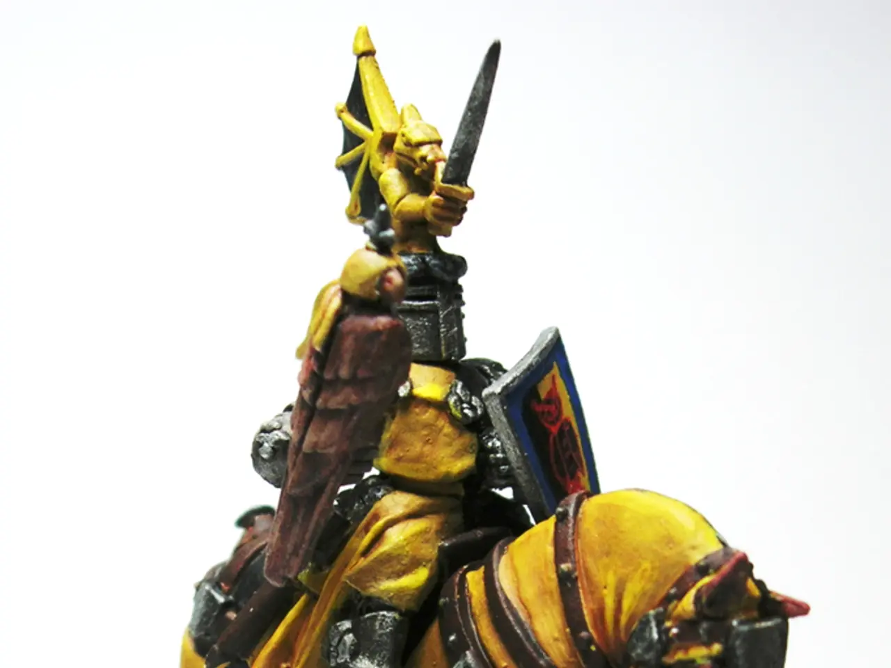 In this image there is a toy sculpture of a man holding a sword and an Armour in the hands and...