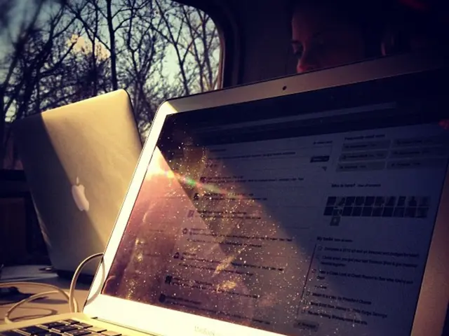 In this image we can able to see a laptop, and there is a person who is working on another laptop,...
