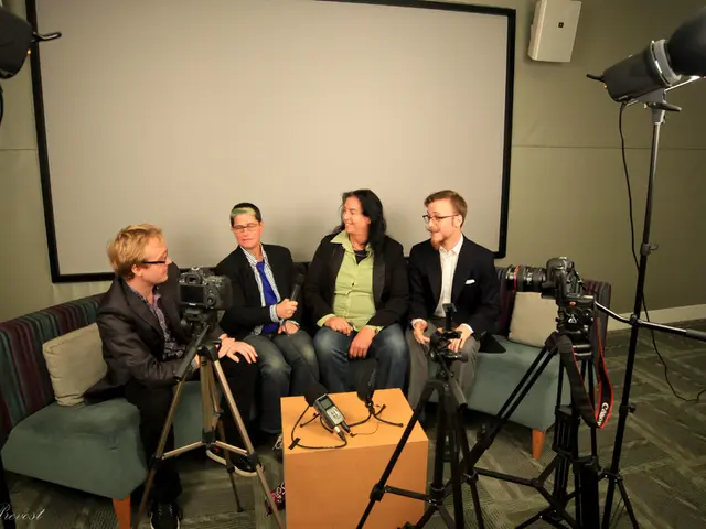 This picture describe about a group of people sitting on the coach and giving interview. Behind...